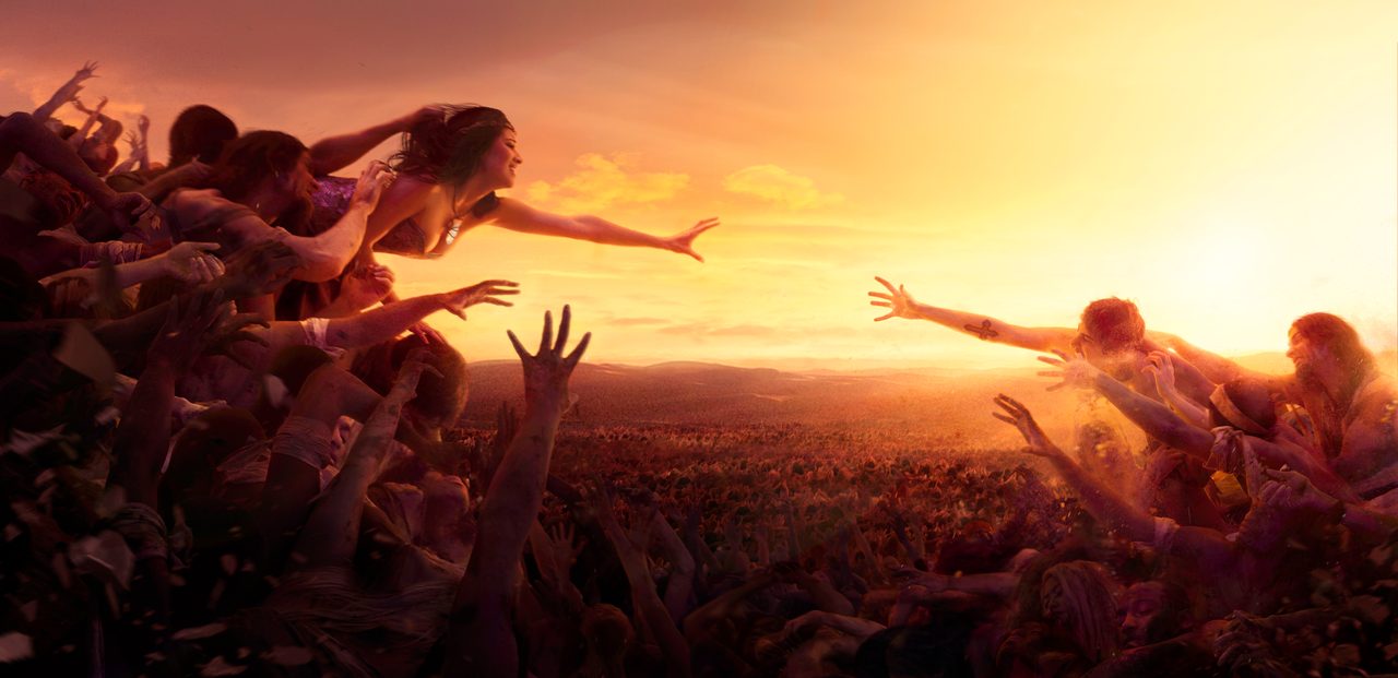 Almost — two crowds of reaching hands stretch towards each other at sunset, a woman leaning out from the top of one