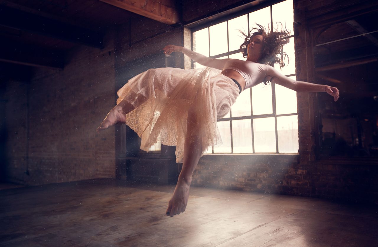 Floating Dancer — a dancer in a pale tulle skirt floats in a sunlit loft